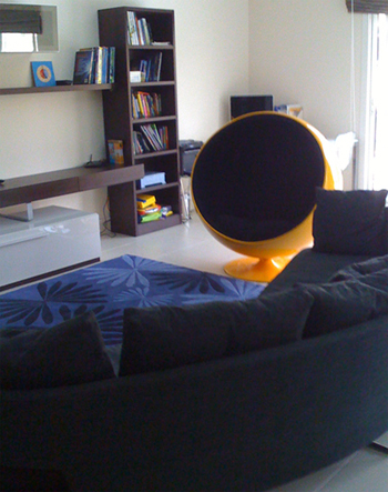 Modern lounge interior with black sofa, blue rug, and yellow accent chair